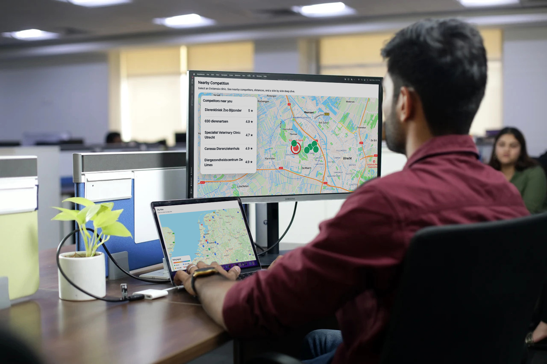 Person working at a desk with two monitors showing maps